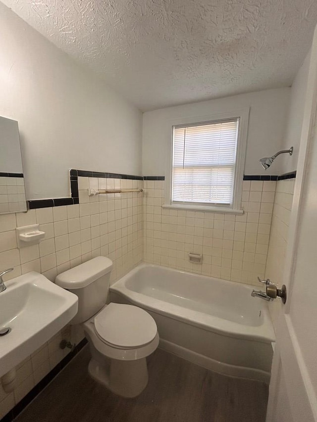 full bathroom featuring toilet, shower / bath combination, hardwood / wood-style floors, and tile walls