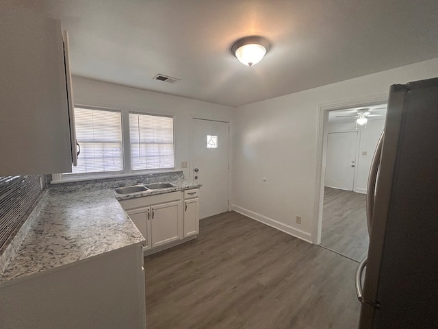 kitchen featuring sink, dark wood-type flooring, stainless steel fridge, and white cabinets