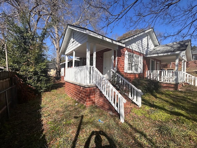 view of side of home featuring a yard and covered porch