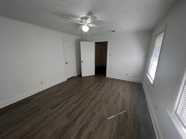 unfurnished room with ceiling fan, dark wood-type flooring, a textured ceiling, and plenty of natural light