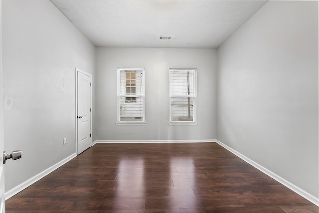 unfurnished room featuring a textured ceiling and dark hardwood / wood-style floors