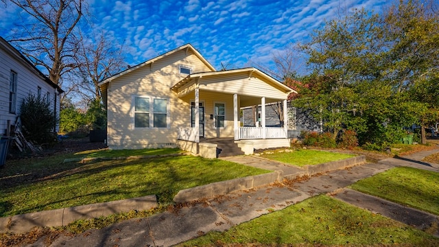 bungalow featuring covered porch and a front yard