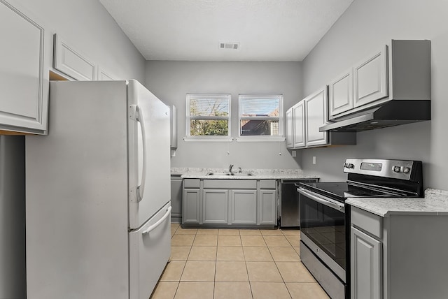 kitchen with gray cabinetry, sink, stainless steel appliances, wall chimney range hood, and light tile patterned floors