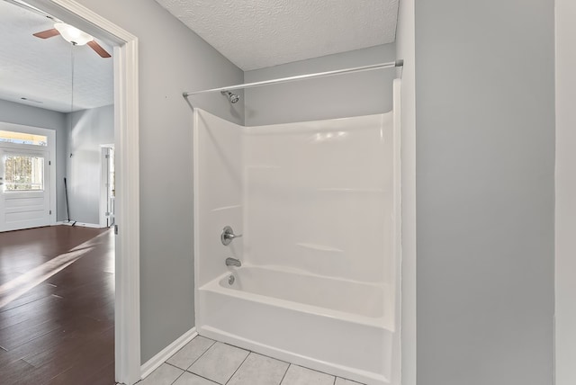 bathroom featuring ceiling fan, tile patterned flooring, a textured ceiling, and tub / shower combination