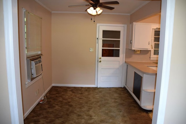 kitchen with ceiling fan, white cabinets, ornamental molding, and dark colored carpet