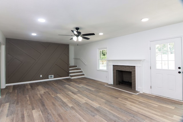 unfurnished living room featuring hardwood / wood-style flooring, ceiling fan, a fireplace, and a wealth of natural light