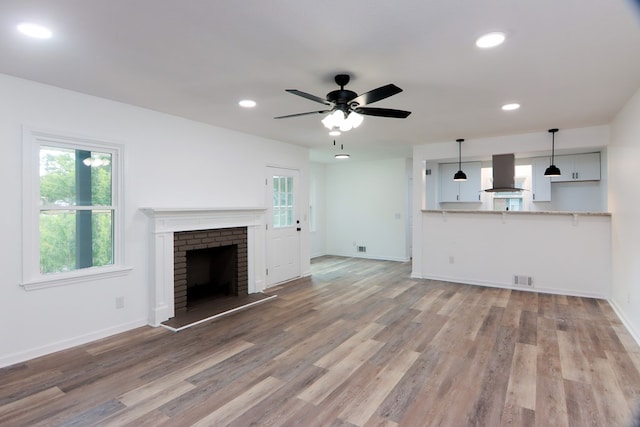 unfurnished living room featuring hardwood / wood-style flooring, ceiling fan, and a fireplace