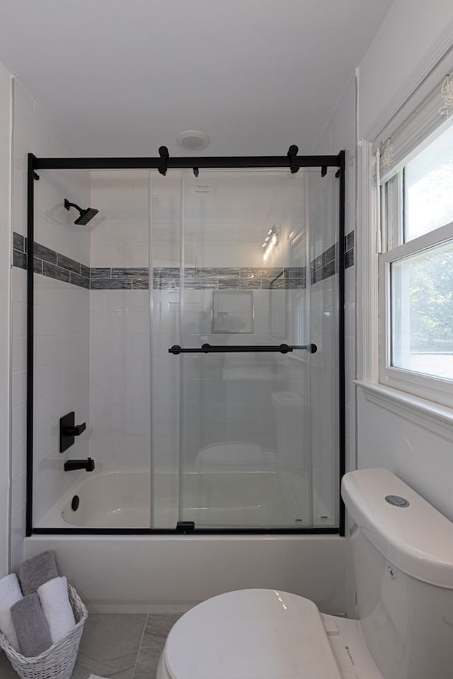 bathroom featuring toilet, tile patterned flooring, and combined bath / shower with glass door