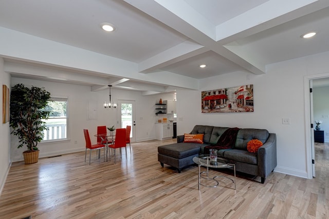 living room with a notable chandelier, beam ceiling, and light wood-type flooring