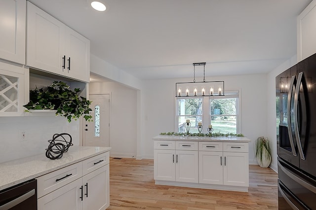 kitchen with white cabinetry, hanging light fixtures, light stone countertops, light hardwood / wood-style floors, and black appliances