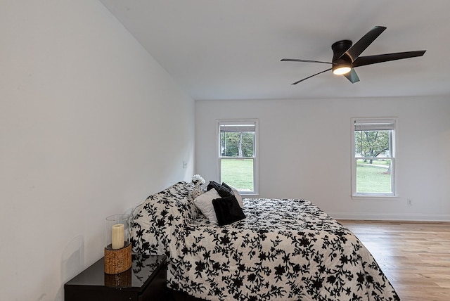 bedroom featuring ceiling fan, light hardwood / wood-style floors, and multiple windows