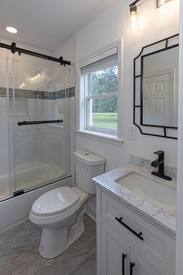 full bathroom with bath / shower combo with glass door, vanity, and toilet