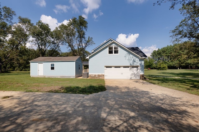 view of front of property featuring a garage, an outbuilding, a front yard, and cooling unit