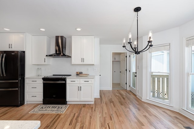 kitchen featuring white cabinetry, hanging light fixtures, black appliances, and wall chimney exhaust hood