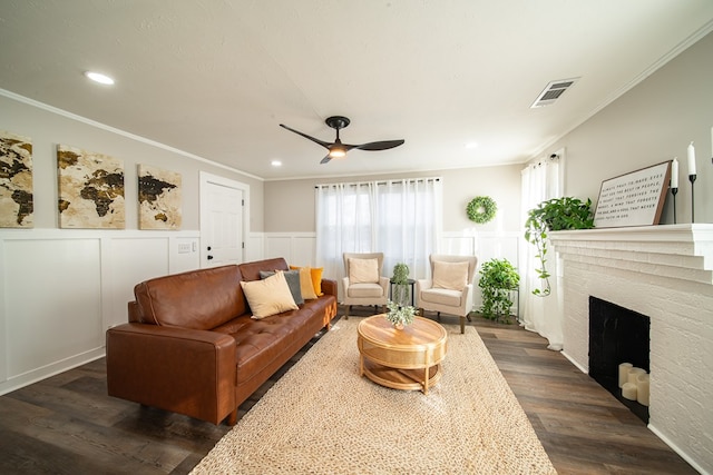 living room featuring a brick fireplace, plenty of natural light, dark wood-type flooring, and ornamental molding