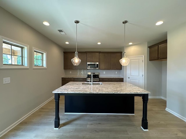 kitchen featuring hardwood / wood-style flooring, light stone counters, and appliances with stainless steel finishes