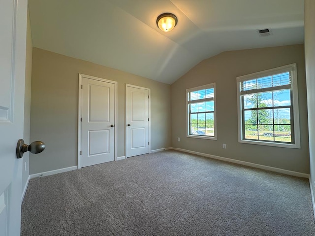 unfurnished bedroom featuring carpet and lofted ceiling