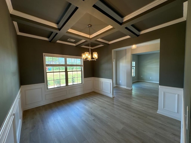 unfurnished room featuring a chandelier, beam ceiling, light hardwood / wood-style flooring, and ornamental molding