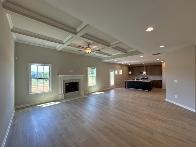 unfurnished living room with a high end fireplace, a wealth of natural light, ceiling fan, and light hardwood / wood-style floors