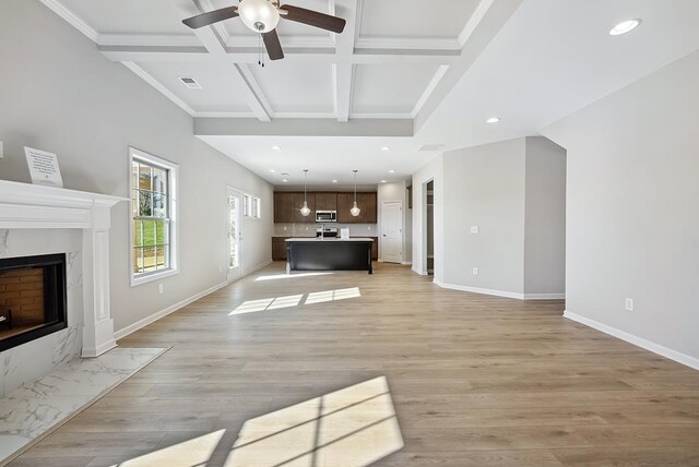 unfurnished living room with a high end fireplace, wood-type flooring, coffered ceiling, and ornamental molding