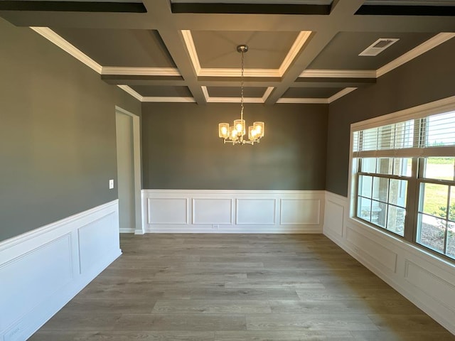 unfurnished dining area featuring coffered ceiling, crown molding, an inviting chandelier, light hardwood / wood-style flooring, and beamed ceiling