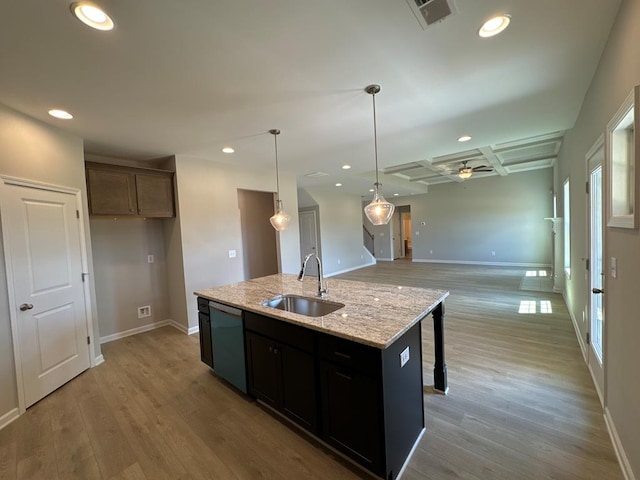 kitchen featuring sink, light stone counters, light hardwood / wood-style flooring, stainless steel dishwasher, and a center island with sink