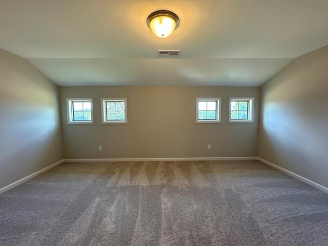 spare room featuring carpet, plenty of natural light, and vaulted ceiling