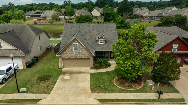 view of front of house with stone siding, a residential view, driveway, a garage, and a front lawn