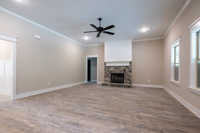 unfurnished living room featuring wood finished floors, a ceiling fan, crown molding, recessed lighting, and a stone fireplace