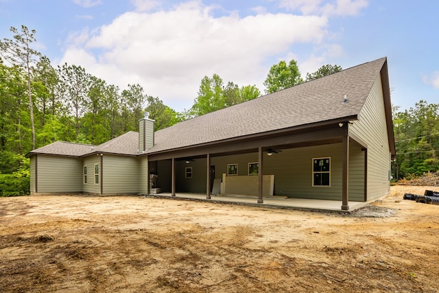 rear view of house with ceiling fan, a patio area, a chimney, and roof with shingles