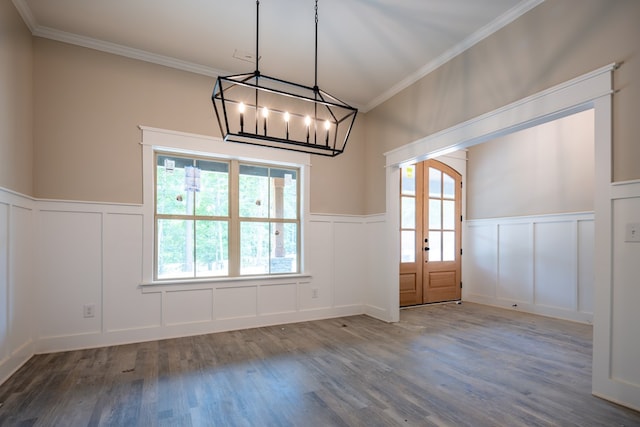 unfurnished dining area with a decorative wall, healthy amount of natural light, a wainscoted wall, french doors, and wood finished floors