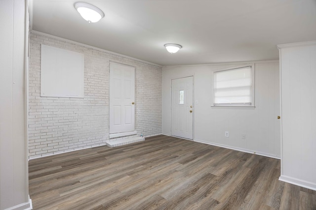 entrance foyer with brick wall, dark hardwood / wood-style floors, and ornamental molding