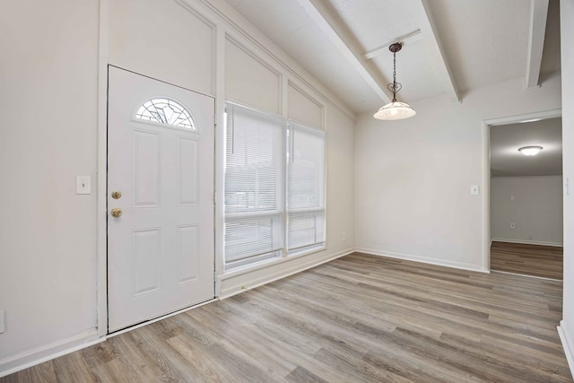 foyer entrance with light wood-type flooring and beam ceiling