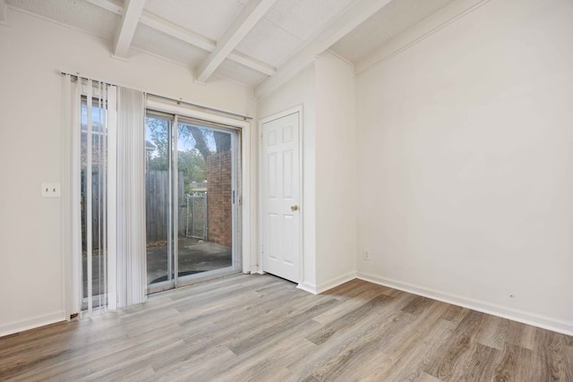 unfurnished room with light hardwood / wood-style floors and beam ceiling