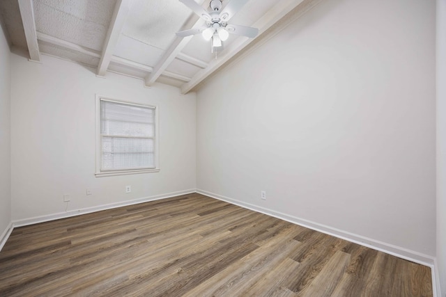 empty room featuring ceiling fan, dark wood-type flooring, and vaulted ceiling with beams