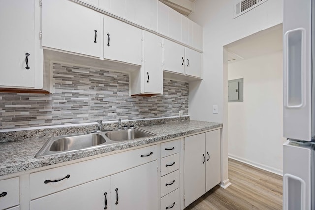 kitchen with light hardwood / wood-style flooring, refrigerator, sink, white cabinets, and decorative backsplash