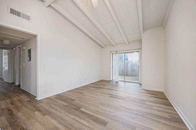 empty room with lofted ceiling with beams and hardwood / wood-style floors