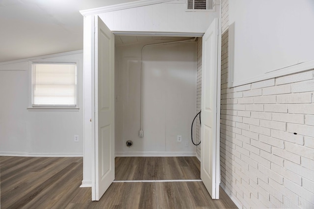 bathroom with hardwood / wood-style flooring, vaulted ceiling, and brick wall