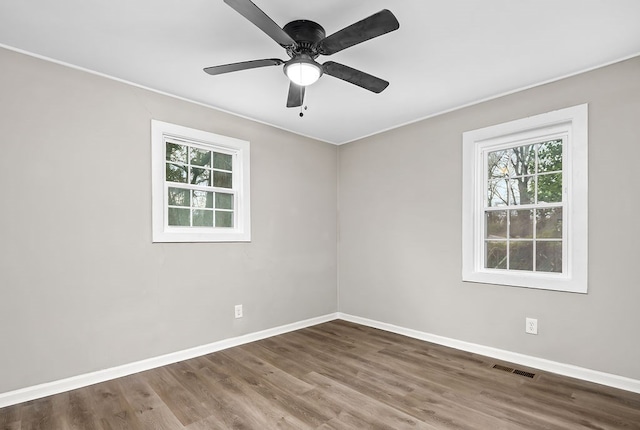 empty room featuring ceiling fan, visible vents, baseboards, ornamental molding, and wood finished floors