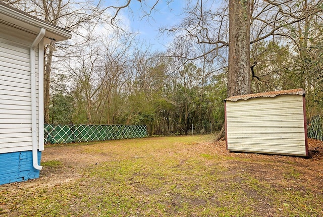view of yard featuring fence, an outdoor structure, and a shed