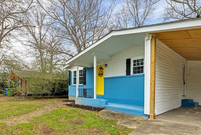 view of exterior entry featuring concrete driveway, a carport, and brick siding