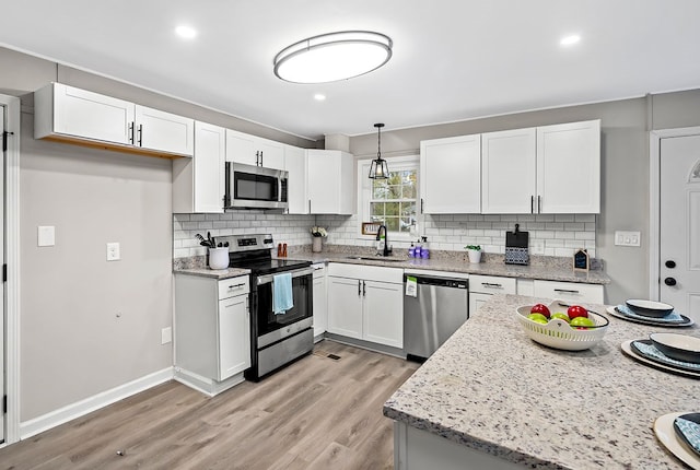 kitchen with light wood-type flooring, stainless steel appliances, white cabinets, and a sink