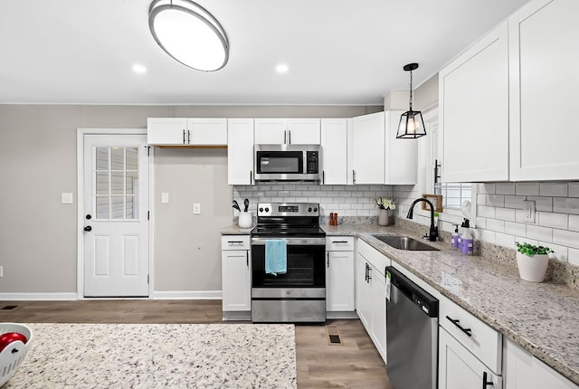 kitchen featuring stainless steel appliances, light wood-type flooring, white cabinets, and a sink