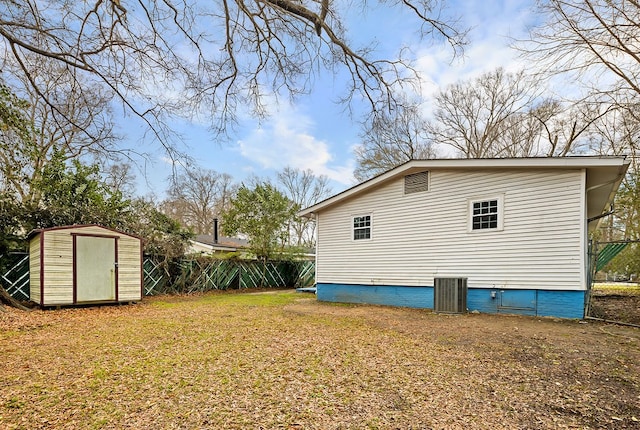 view of property exterior with a storage unit, an outbuilding, crawl space, fence, and central AC