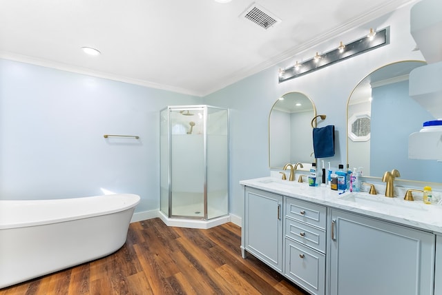 bathroom with wood finished floors, a sink, visible vents, a freestanding bath, and crown molding