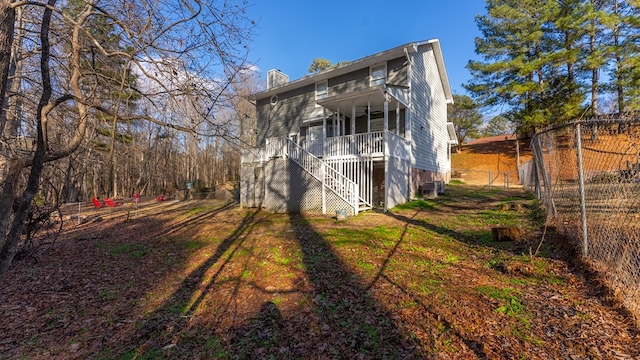 rear view of house featuring a fenced backyard, a chimney, and stairway