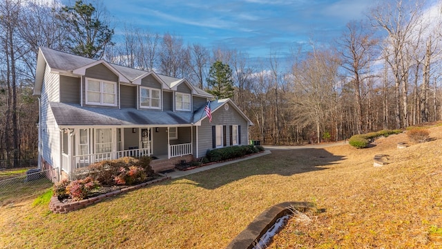 view of front of house with a front yard, covered porch, and roof with shingles