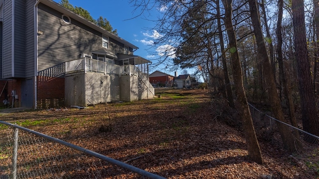 view of side of property with stairs, fence, a deck, and brick siding