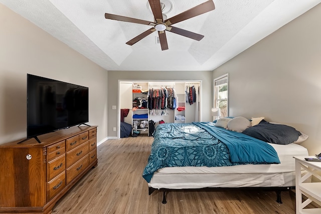 bedroom with a closet, light wood-style floors, a ceiling fan, a textured ceiling, and baseboards