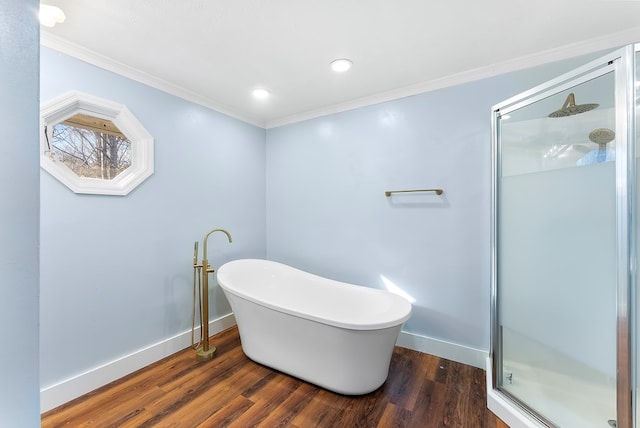 bathroom with ornamental molding, a shower stall, wood finished floors, a freestanding tub, and baseboards